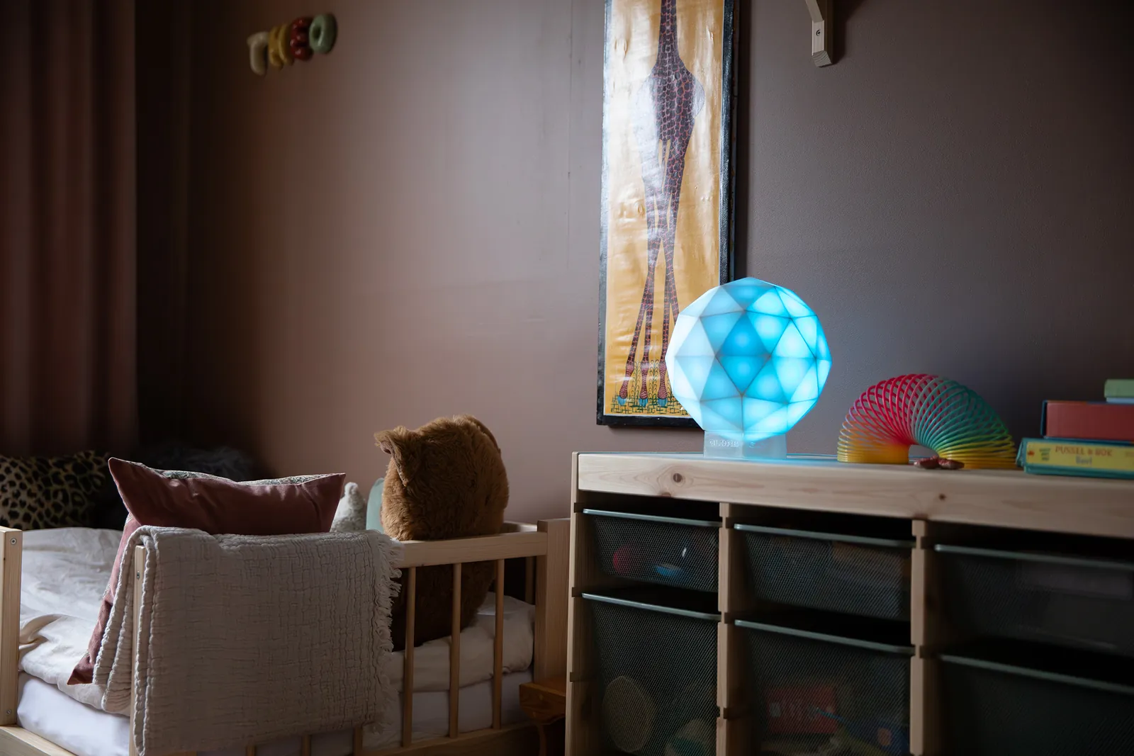 Eine hellblau leuchtende GLORB auf einem Regal im Kinderzimmer
